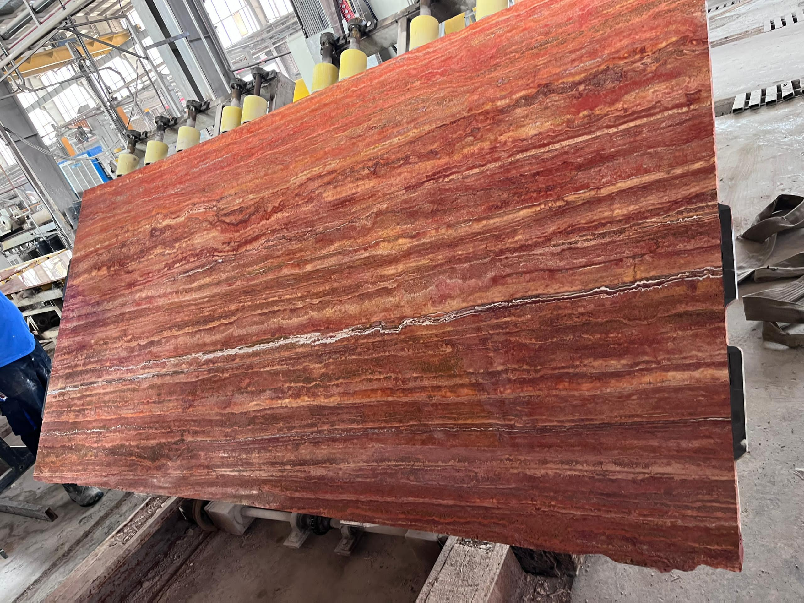 Close-up of a red Titanium Travertine slab showcasing red and golden veining.